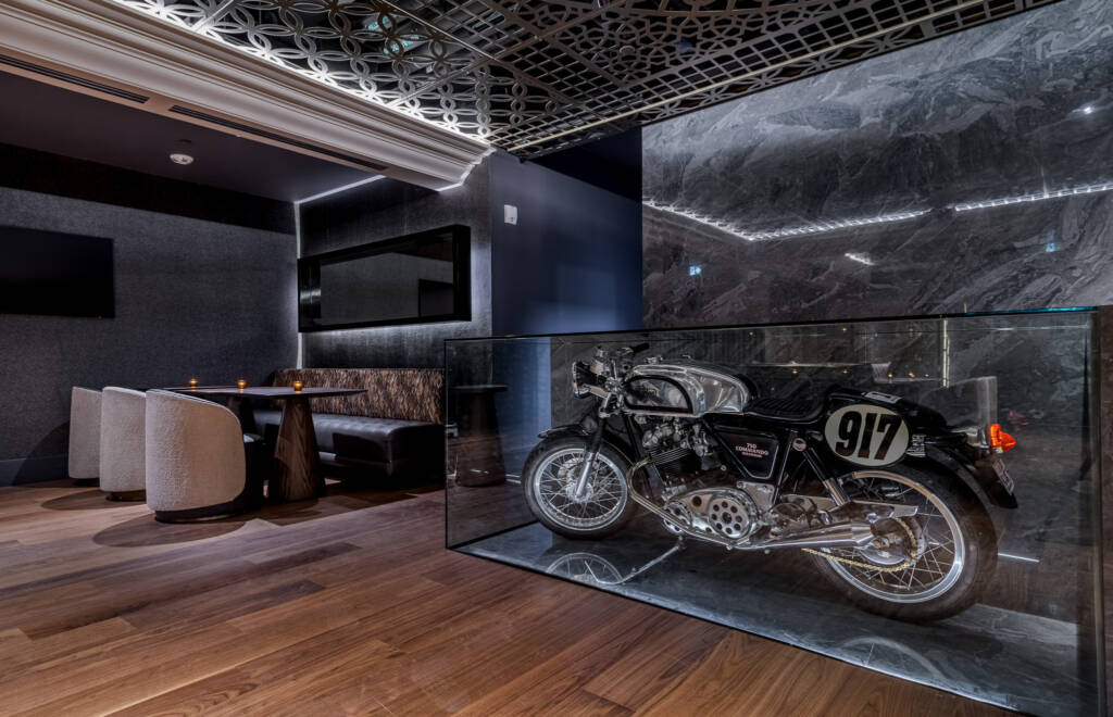 restaurant tables in the back and a decorative motorcycle inside glass box
