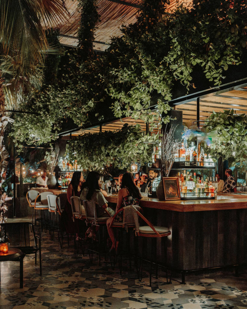 counter of a bar with jungle themed decor with people sitting on high bar stools
