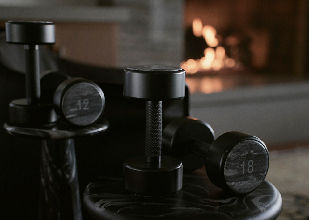 12lb and 18lb dumbbells on black table and fireplace in the background