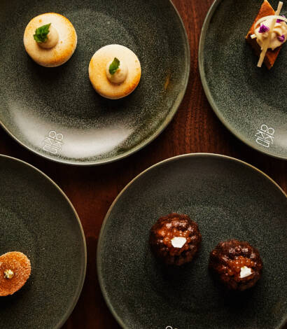 assortment of desserts plated on black plates on a wooden table