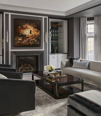 living room with grey couch, black arm chair, beige rug, fireplace in the back